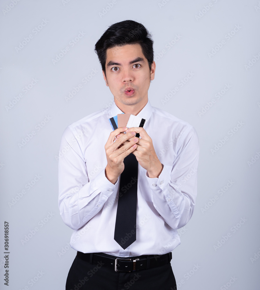 Portrait handsome young asian man wearing a white shirt holding credit card and smile isolated on white background. Asian man people. business success concept. Portrait handsome young asian man wearing a white shirt holding credit card and smile isolated on white background. Asian man people. business success concept.