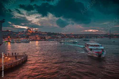Istanbul, Turkey: November 30, 2019: Moody illuminated ferry and Galata Tower during twilight. © Solidasrock