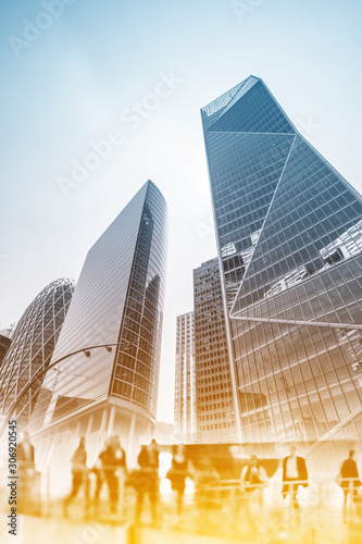 Silhouettes of people walking in the street near skyscrapers and modern office buildings in Paris business district. Multiple exposure image. Economy, finances, business concept illustration.	