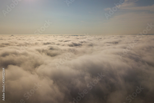 Aerial view over white clouds and clear blue sky.