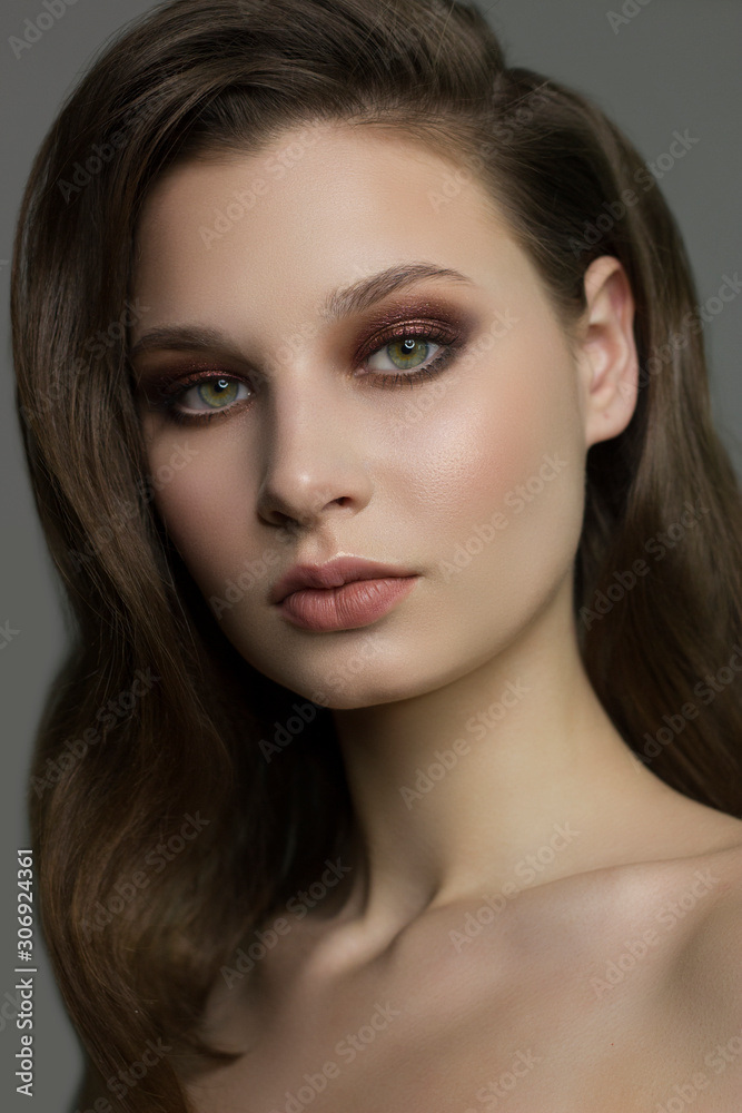 Close-up portrait of beautiful woman's purity face with dark green smoky-eyes make-up, pale full lips. Sexy model with clean shiny skin, purity complexion