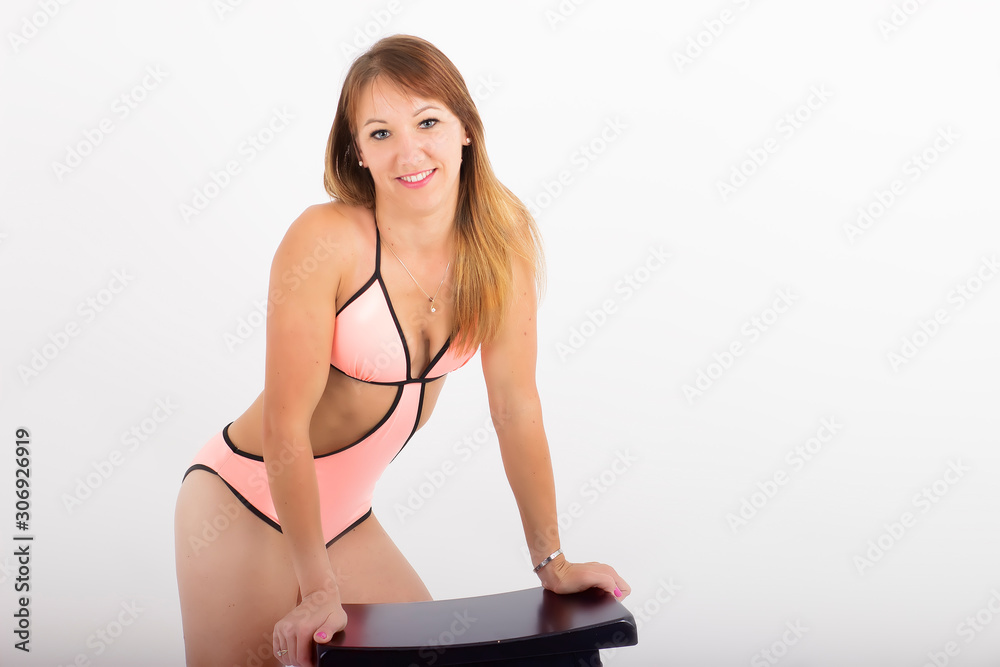 Young woman dressed in a bikini with a small breast pose. White background  Stock Photo