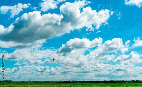 Commercial airline flying on blue sky and white fluffy clouds. Passenger plane after take off or going to landing flight. Vacation travel abroad. Air transportation. Area around the airport.