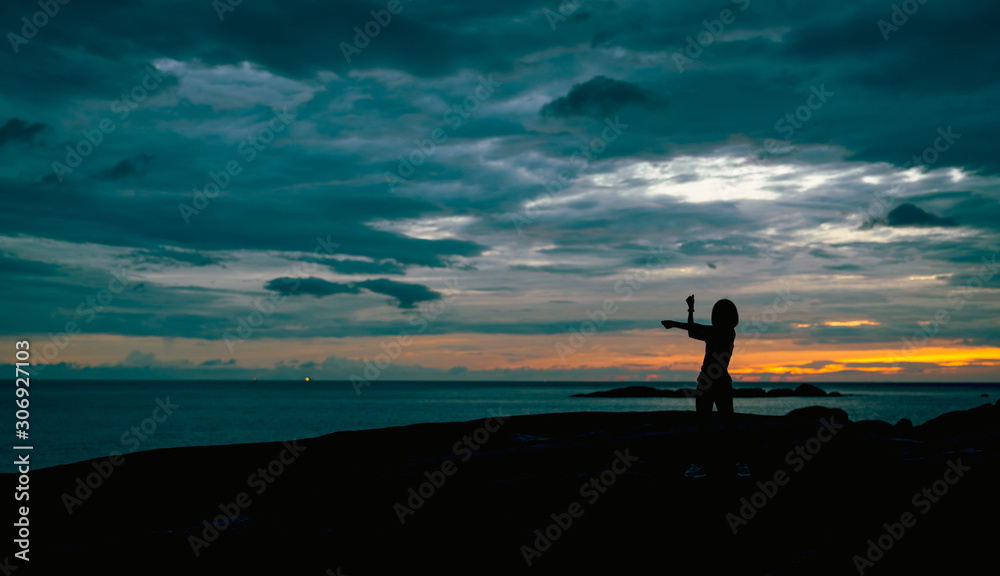 Silhouette woman workout in the morning at stone beach with beautiful sunrise sky. Fit woman stretching body before workout. Exercise for healthy lifestyle. Out door workout. Nature landscape. Freedom
