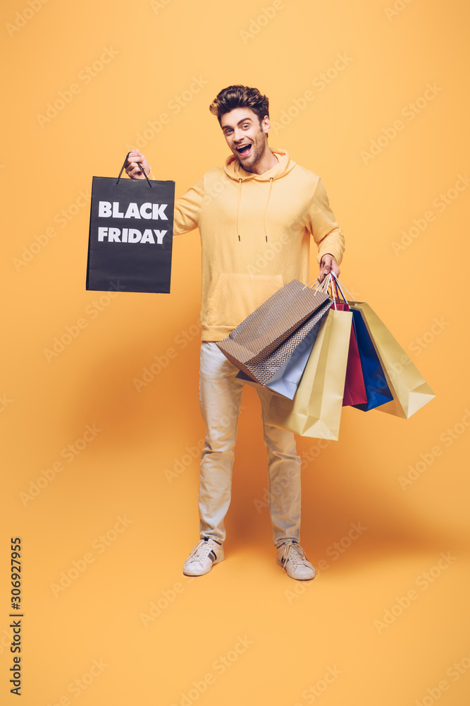 emotional man holding shopping bags on black friday, on yellow emotional man holding shopping bags on black friday, on yellow
