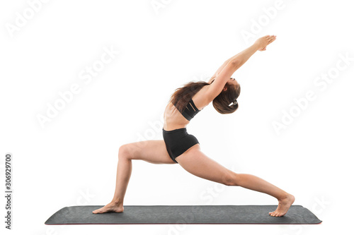 Brunette girl doing yoga in a black sports swimsuit on a white background