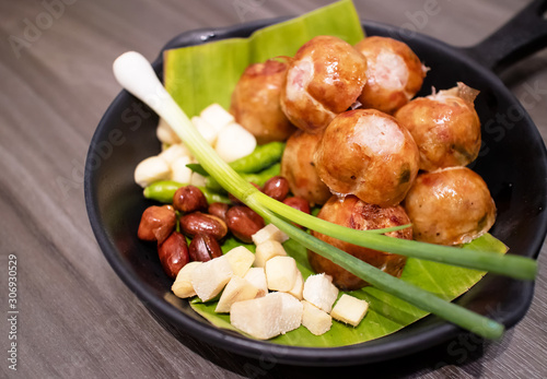 Isan Sausage or Thai Sausages with chilli, garlic, galangal, spring onion and peanut serving on banana leaf in small black pan