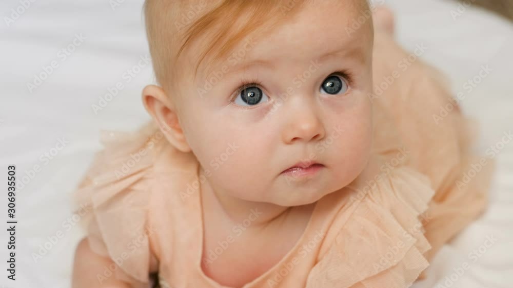 Beautiful Smiling Baby: A gorgeous little baby girl lies on white blanket and smiles at the camera with a nice big eyes. close up 4k video Beautiful Smiling Baby: A gorgeous little baby girl lies on white blanket and smiles at the camera with a nice big eyes. close up 4k video