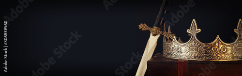 low key image of beautiful queen/king crown over antique box next to sword. fantasy medieval period. Selective focus