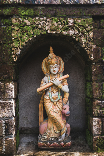 Traditional balinese style statue as decoration in hotel garden. Religious handmade hindu statuette. Old and vintage ritual details in Bali house temple.