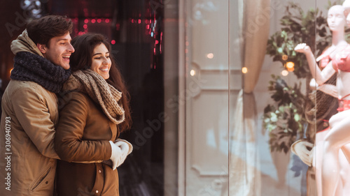 Couple Embracing Standing Outside Of Store In Winter Night, Panorama