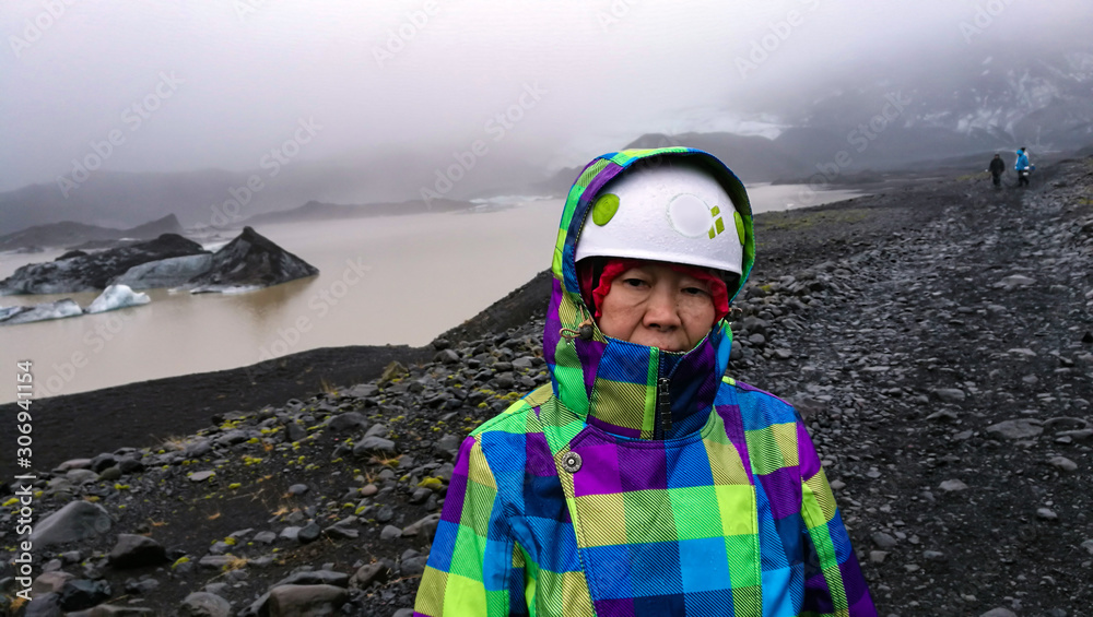 Asian old senior woman hiking on glacier volcanic landscape in Iceland to see ice cave Asian old senior woman hiking on glacier volcanic landscape in Iceland to see ice cave