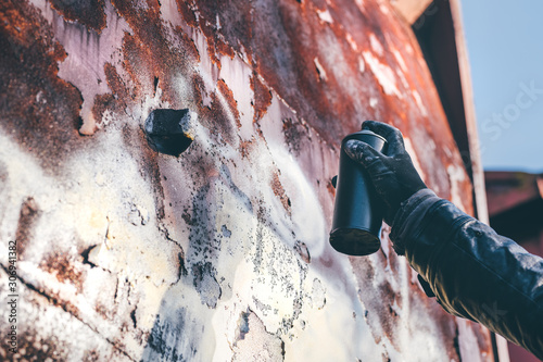 Фотография Homeless man spray painting old train wagon with aerosol can