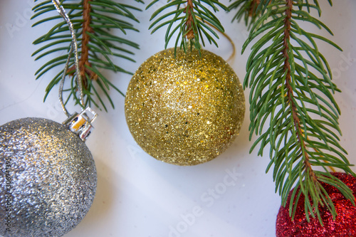 Close-up of shiny christmas toys, balls with glitter, branches of pine tree on white background