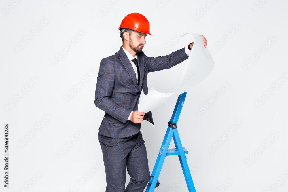The happy engineer architect in suit with a paper go up on the ladder on the white background The happy engineer architect in suit with a paper go up on the ladder on the white background