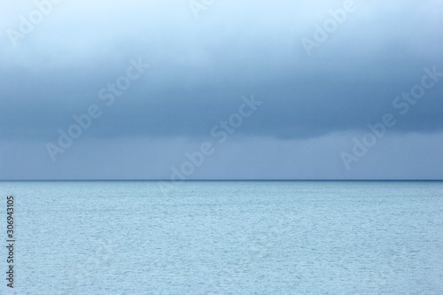 Small white yacht, turquoise blue sea and dark blue sky with clouds, a rainy day photo