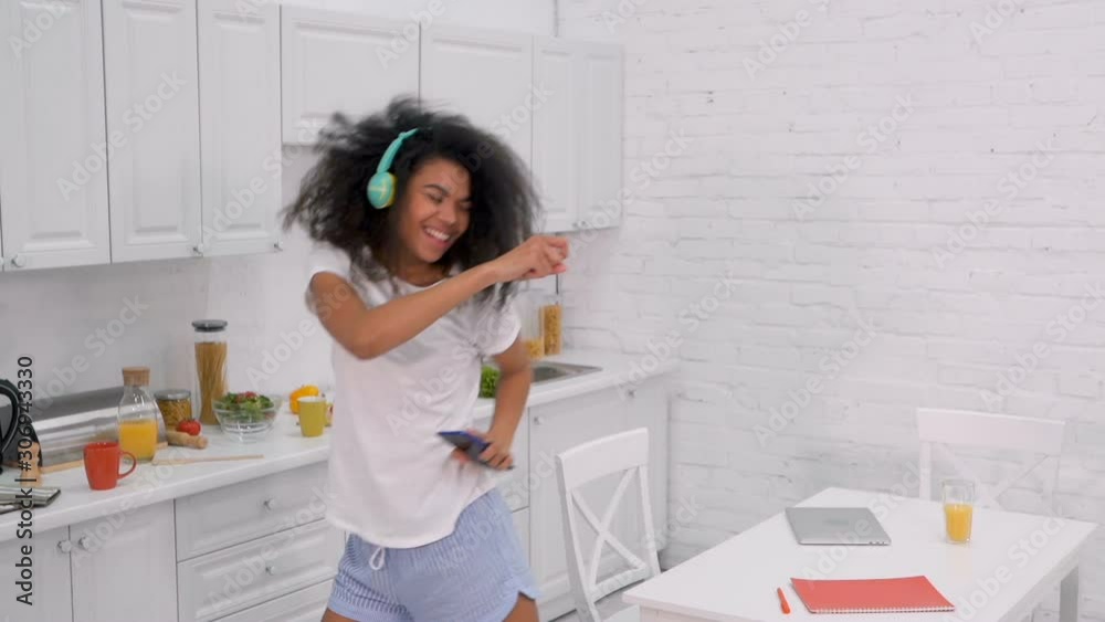 Young afro american woman singing, dancing and having fun at the morning in the kitchen. Slowmotion. Young afro american woman singing, dancing and having fun at the morning in the kitchen. Slowmotion.
