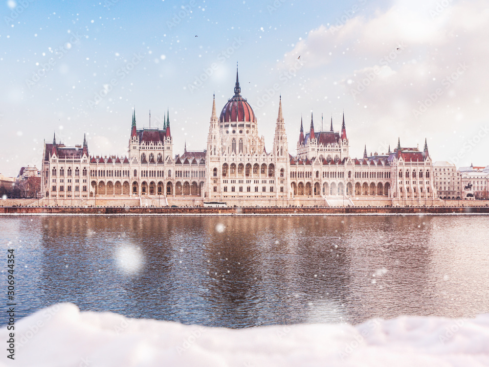 Fototapeta premium Budynek parlamentu węgierskiego w zimie ze śniegiem. Śnieg leży nad brzegiem rzeki w Budapeszcie