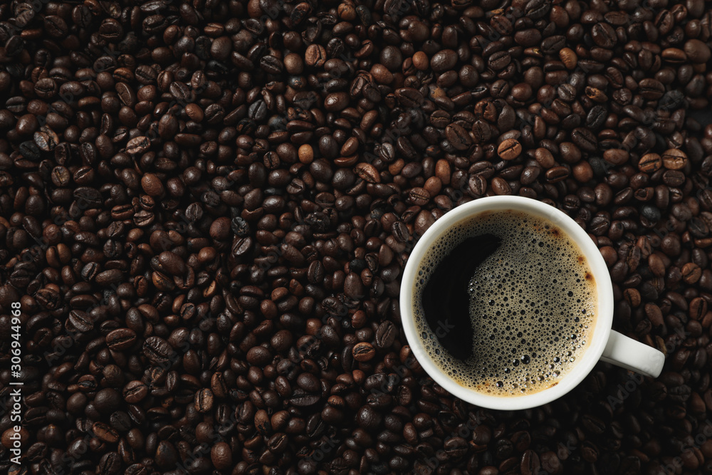 Cup of coffee on coffee beans background, top view Cup of coffee on coffee beans background, top view