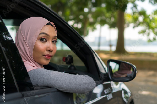 Cute Asian girl wearing hijab looking thru car windows