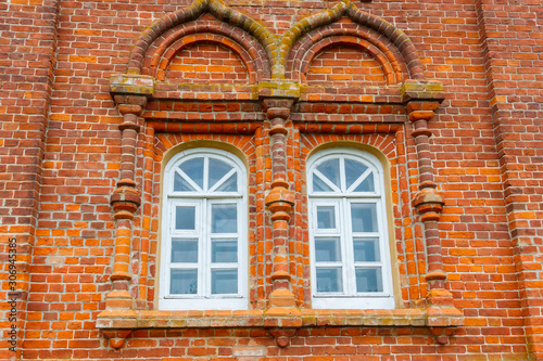 Two rounded windows on old red brick wall
