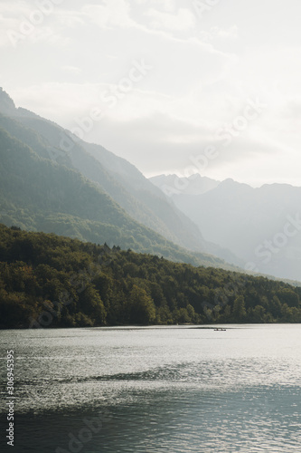 Obraz na płótnie Mountain lake Bohinj in Triglav National Park, Slovenia. Lake in the foreground, misty mountains in the background. Boat in the middle of lake. Sunrise on the lake w salonie