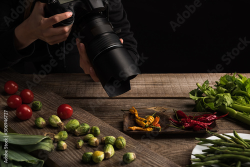 cropped view of female photographer making food composition for commercial photography and taking photo on digital camera