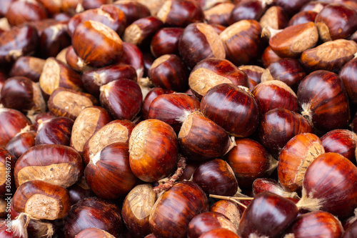 Heap of ripe raw chestnuts closeup, selective fokus.
