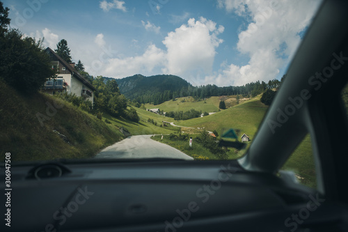 way through mountain village on a Sunny Summer day. old route in the foreground, mountains in the background. view through the windshield of the car