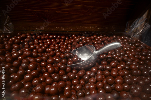 candy tray nuts in brown chocolate with metal scoop in candy store