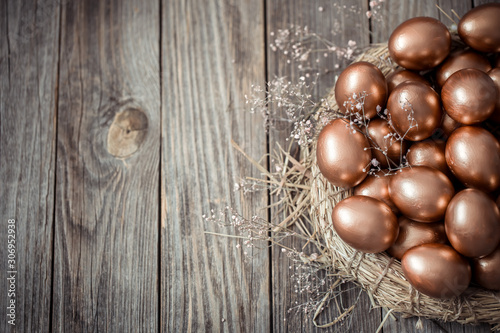 Background with Golden Easter eggs on wooden background.
