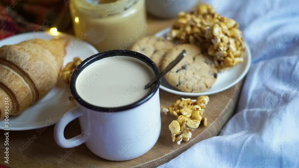 Simple country home breakfast in bed, coffee with milk and homemade pastry on plaid blanket Simple country home breakfast in bed, coffee with milk and homemade pastry on plaid blanket