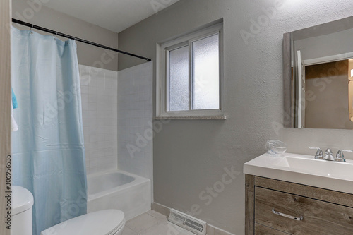 Small bathroom in new model home with window  blue shower curtain  and contemporary cabinet  sink  and fixtures