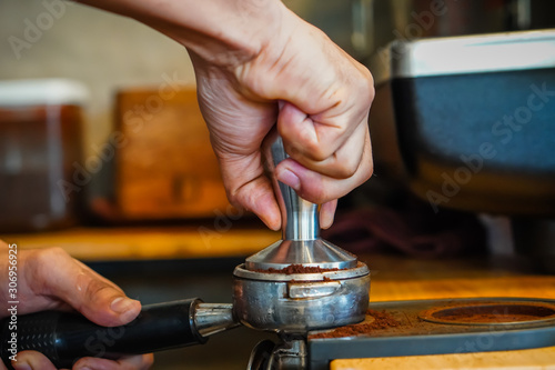 Focus Selection : The barista's hand is holding a filter and pressing the coffee to make an espresso