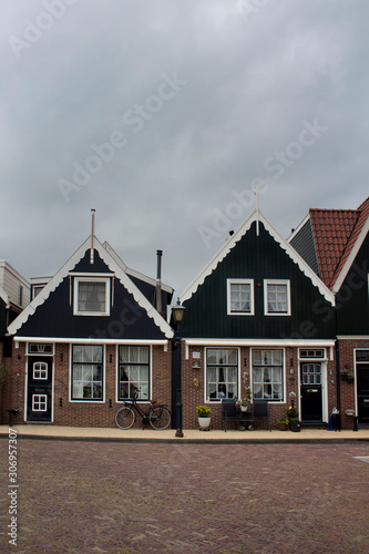 Fototapeta Naklejka Na Ścianę i Meble -  View of historical and traditional houses, plants, bicycle and flowers in Volendam. It is a Dutch town, northeast of Amsterdam. It’s known for its colorful wooden houses and the old fishing boats.