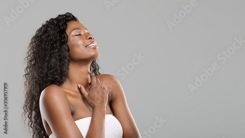Fotografie Delighted beautiful afro girl enjoying touching her soft skin