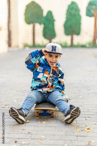 Fototapeta Naklejka Na Ścianę i Meble -  Cute little kid sittinng on his skateboard