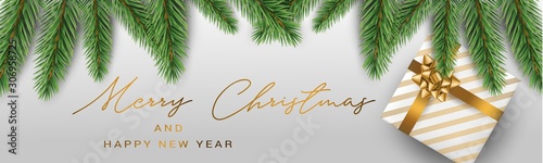 Merry Christmas banner or header. White present box with golden bow under green fir tree branches on silver background. Realistic vector illustration.