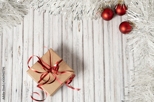 Gift box on a wooden table decorated with a garland and red Christmas balls for the New Year or XMAS. Mail, courier or delivery service concept. Copy space, top view