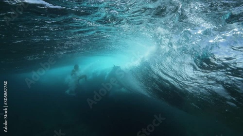 Underwater footage of a breaking wave with a surfboard seen from the water.