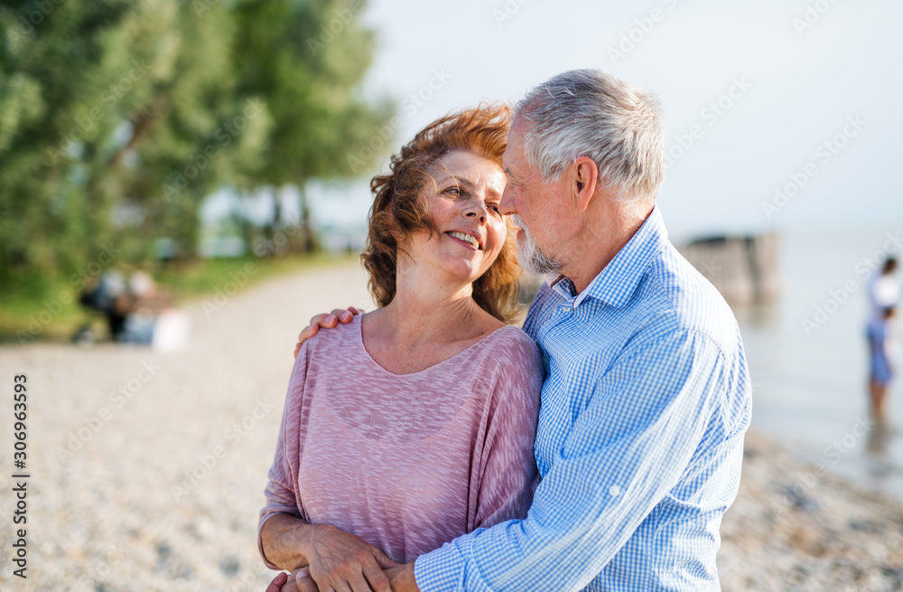 Obraz premium Senior couple on a holiday on a walk by the lake, hugging.
