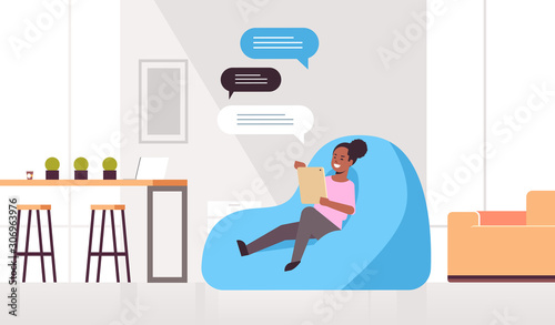 woman chatting messaging african american girl sitting at bean bag using mobile app social network chat bubble communication concept modern living room interior full length horizontal vector
