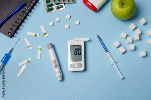 Medicine, healthcare, technology and online pharmacy concept. A diabetic measures your blood glucose. Top down view of pills, glucometer, syringe. World Diabetes Day, November 14th.