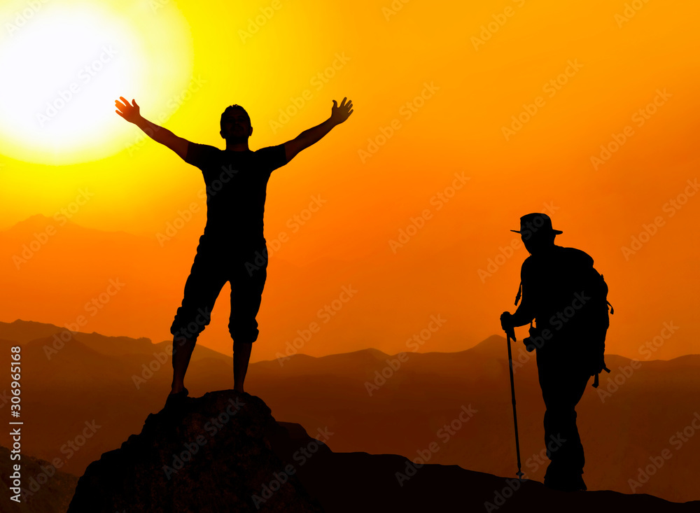 Happy celebrating winning success man at sunset or sunrise standing elated with arms raised up above her head in celebration of having reached mountain top summit goal during hiking travel trek.
