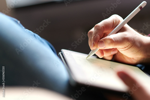 Hand schreibt mit einem Eingabestift auf einem Tablet photo