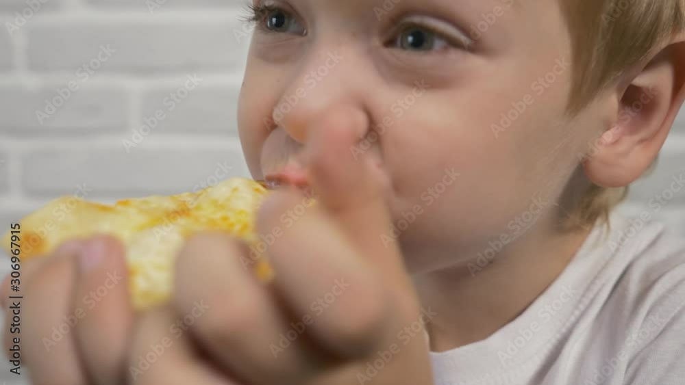 The boy is eating pizza. Unhealthy diet. Fast food home The boy is eating pizza. Unhealthy diet. Fast food home