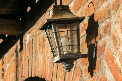 The aftersoon son reflects on a traditional brick wall with a metal lantern with a shadow reflecting the silloute of the latern photo