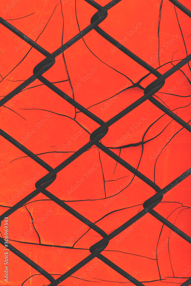 Fototapeta premium Red background of old peeling paint and mesh netting.