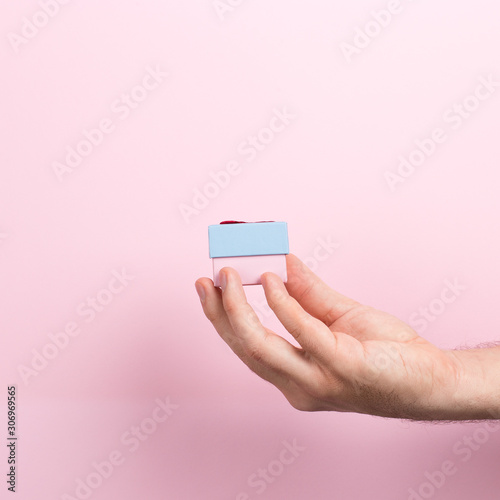 Male hand on a pink background holding craft gift. Christmas concept symbol, commercial bucket print, copy space.