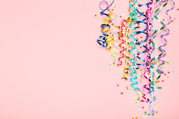 Colorful ribbons with confetti on pink background
